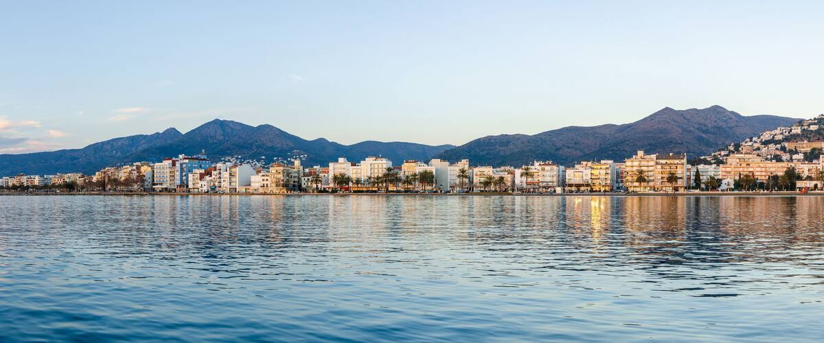 A coastal cityscape with a mountain range in the background.