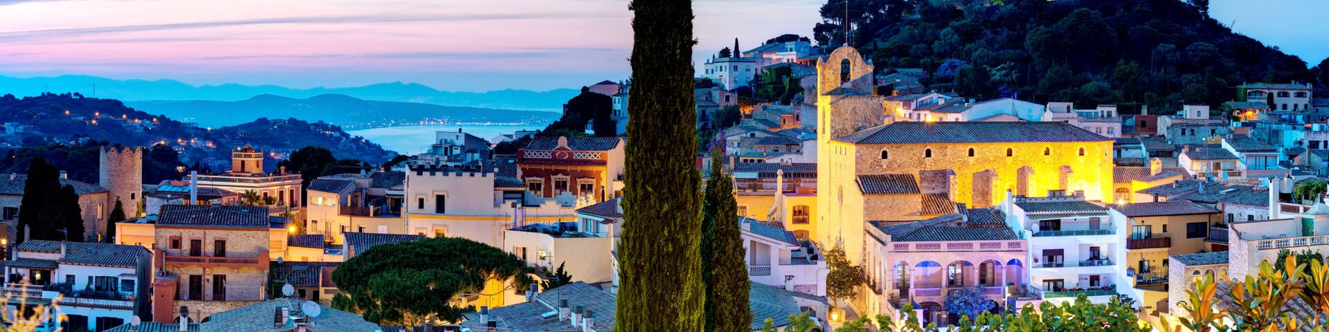 A coastal town with historic architecture, a prominent tower, and a castle on a hill.