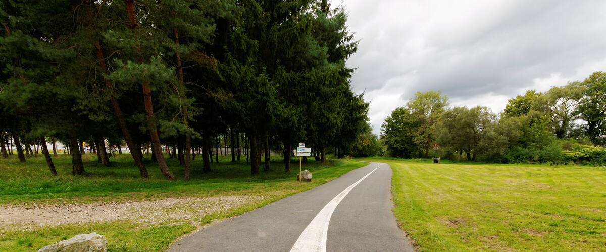 A paved road with a white line down the center, surrounded by trees and grass.