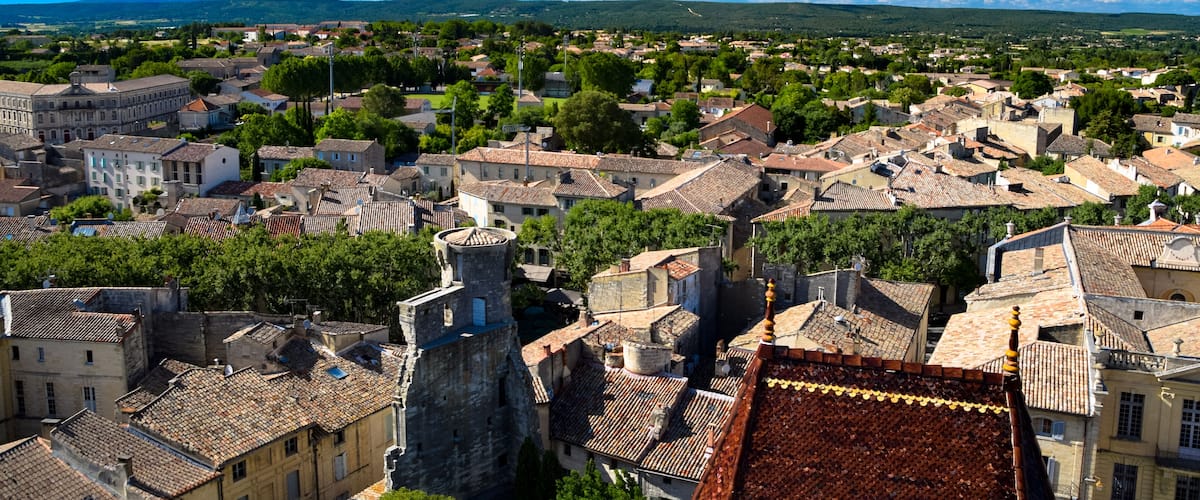 A town with historic buildings, a prominent tower, and a clear blue sky.