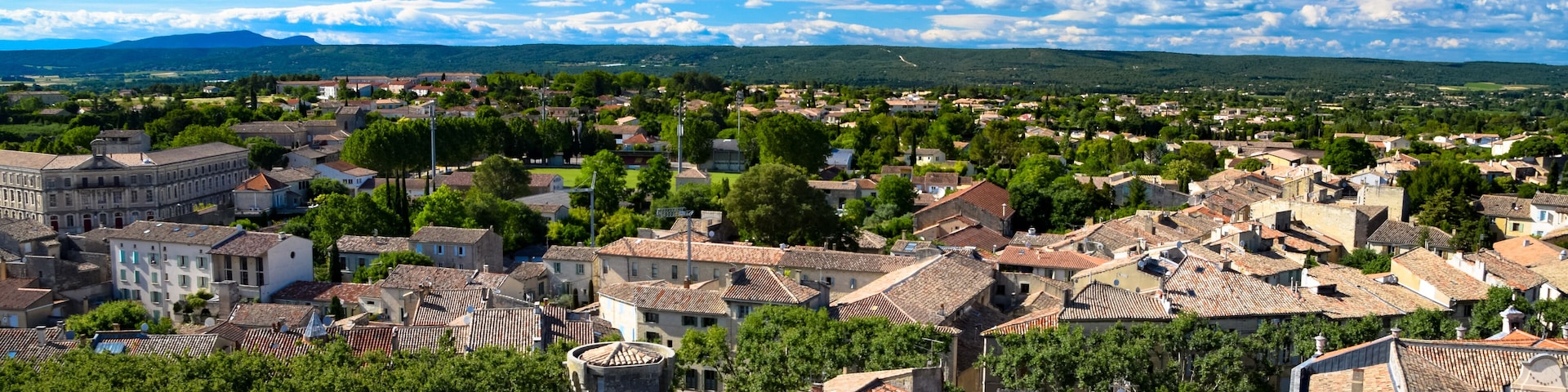 A town with historic buildings, a prominent tower, and a clear blue sky.