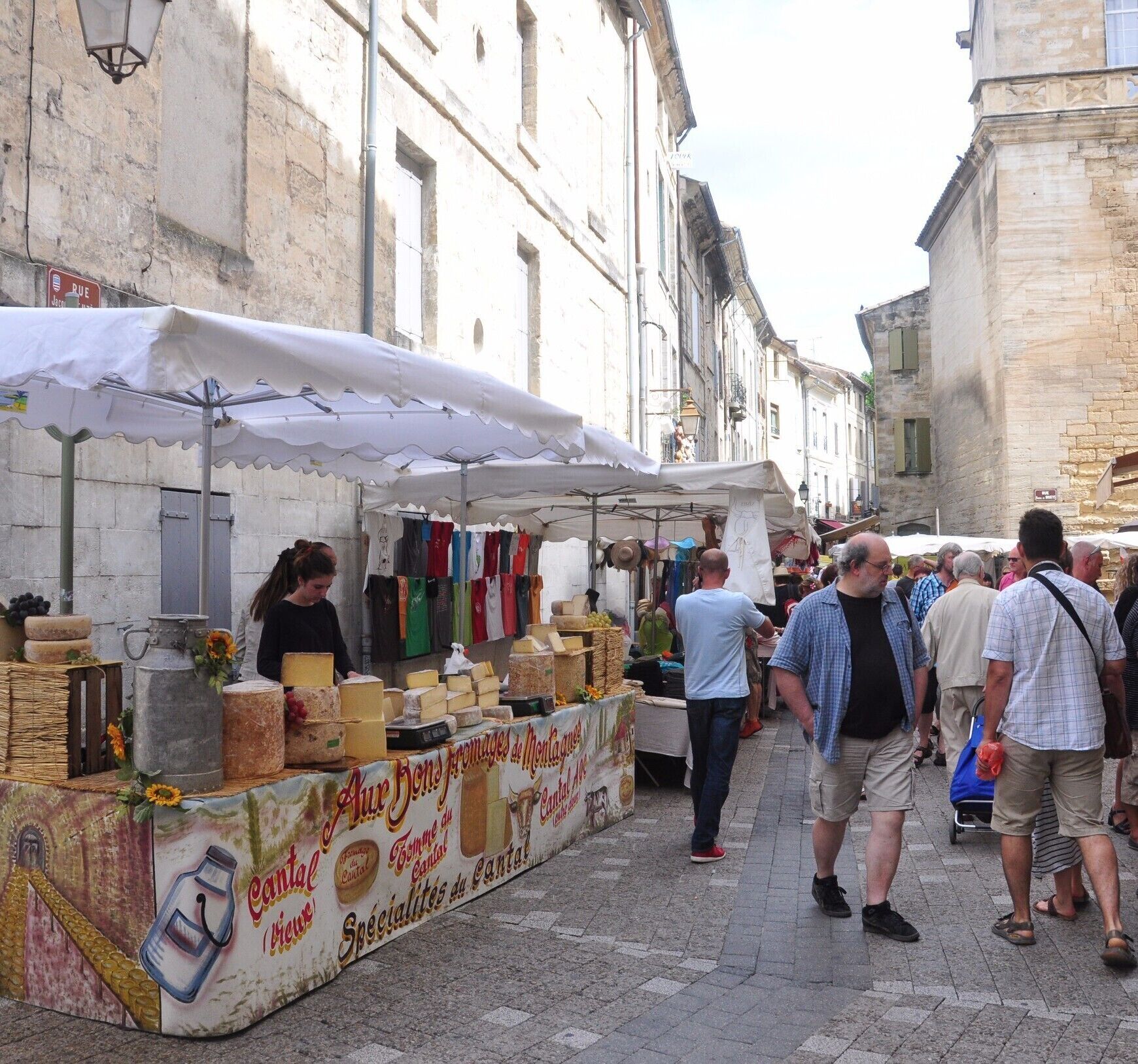 A street market with a cheese stall and people walking.