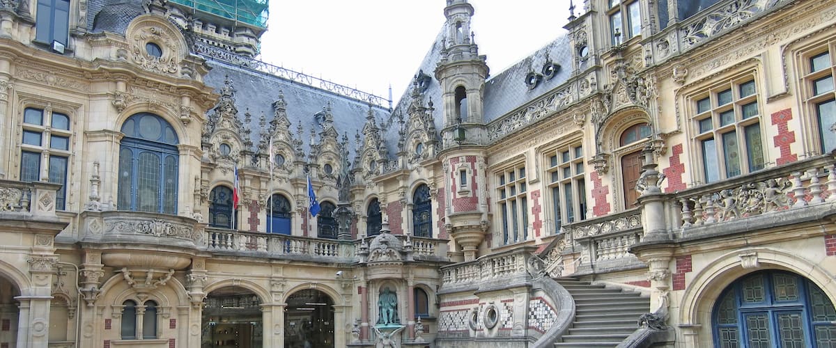A historic building with ornate architecture, including a central staircase and multiple statues.