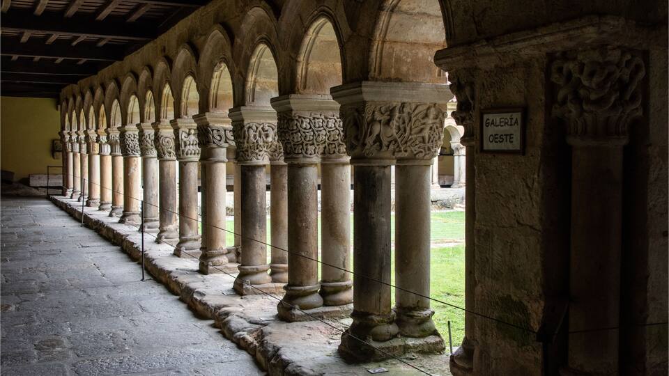 A series of stone columns with intricate carvings, leading to a covered walkway.