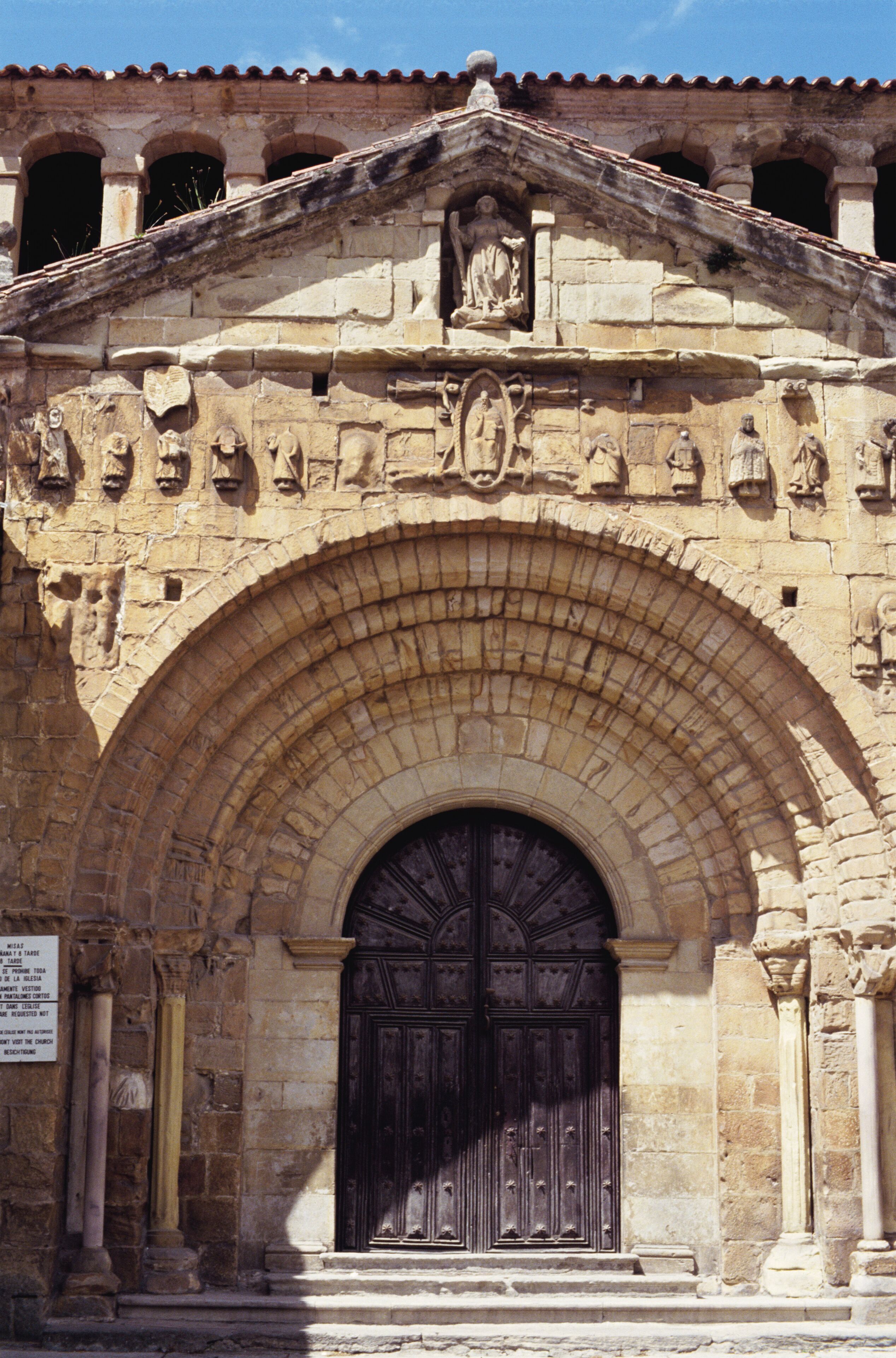 A historic stone building with a large arched doorway, columns, and detailed carvings.