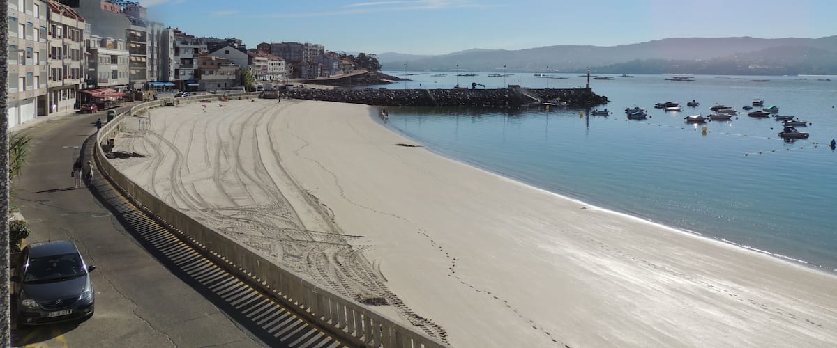 A beach with a road and buildings along the shore.