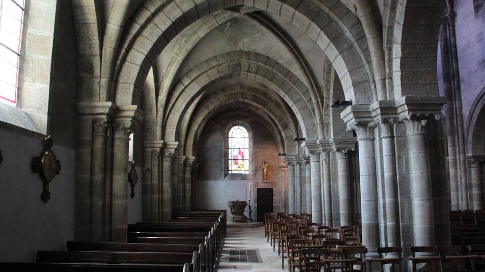 An interior of a church with arched ceilings and rows of pews.