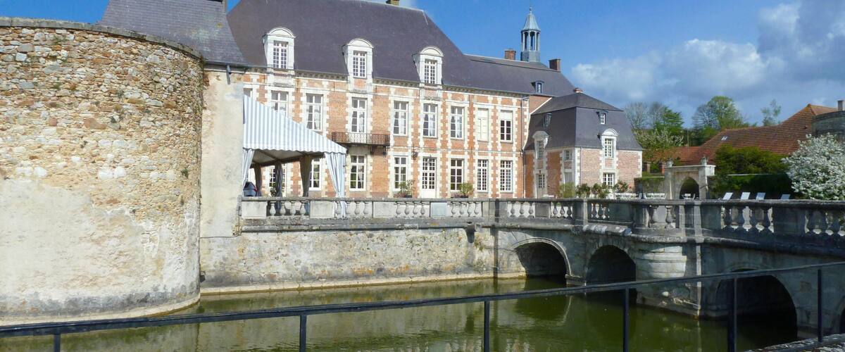 A historic building with a stone wall and a bridge over a canal.