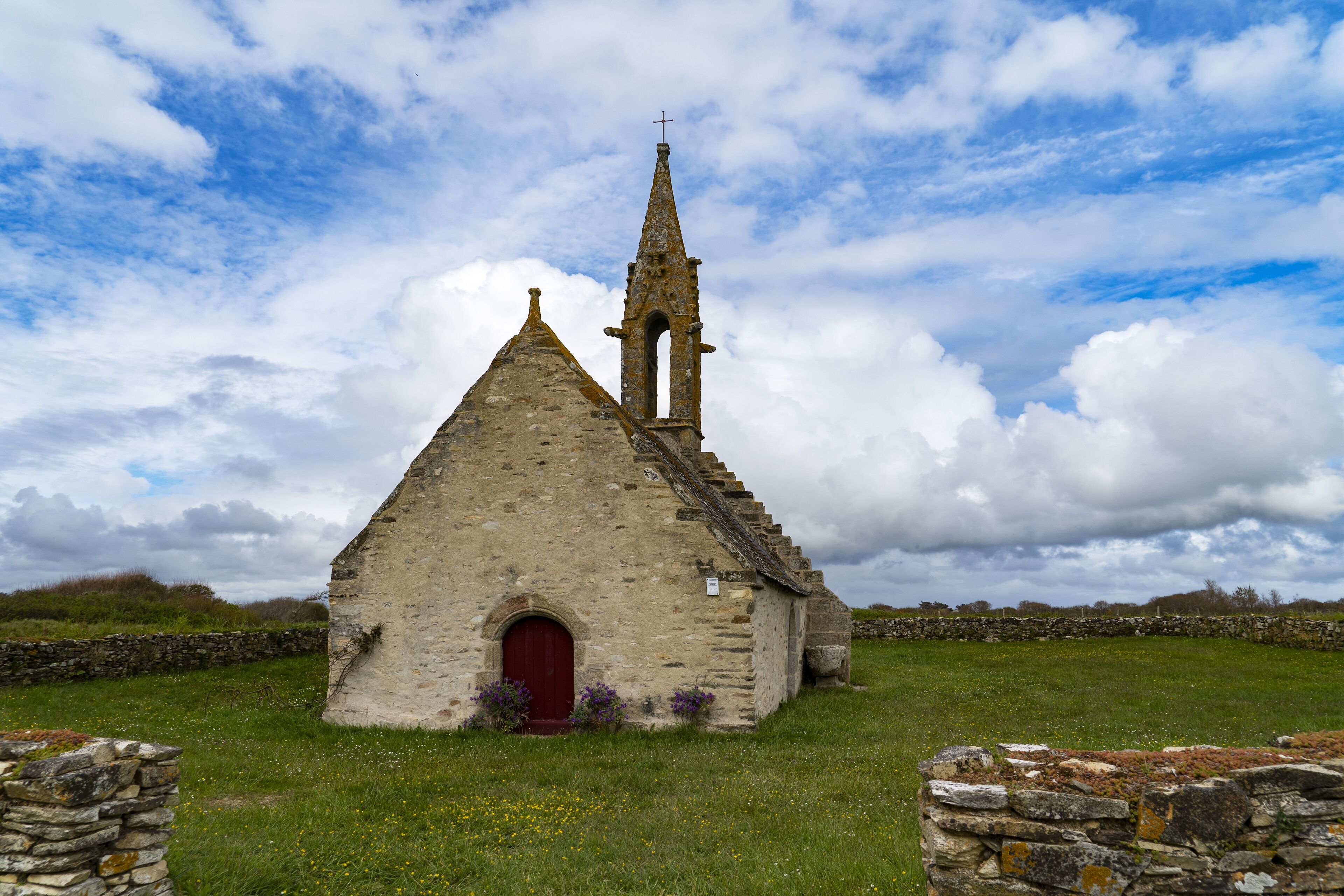 A stone church with a red door and a bell tower.
