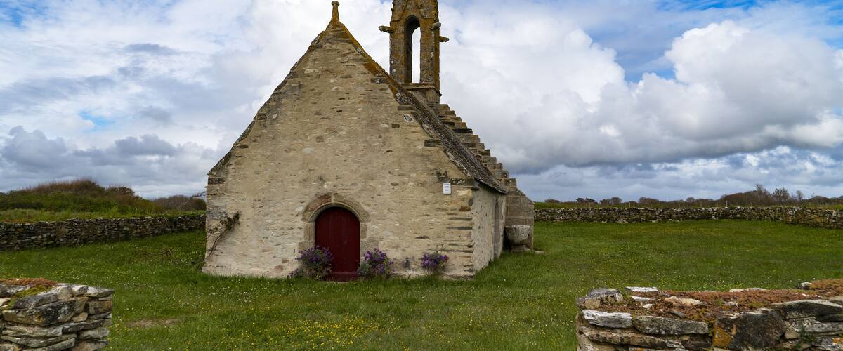 A stone church with a red door and a bell tower.