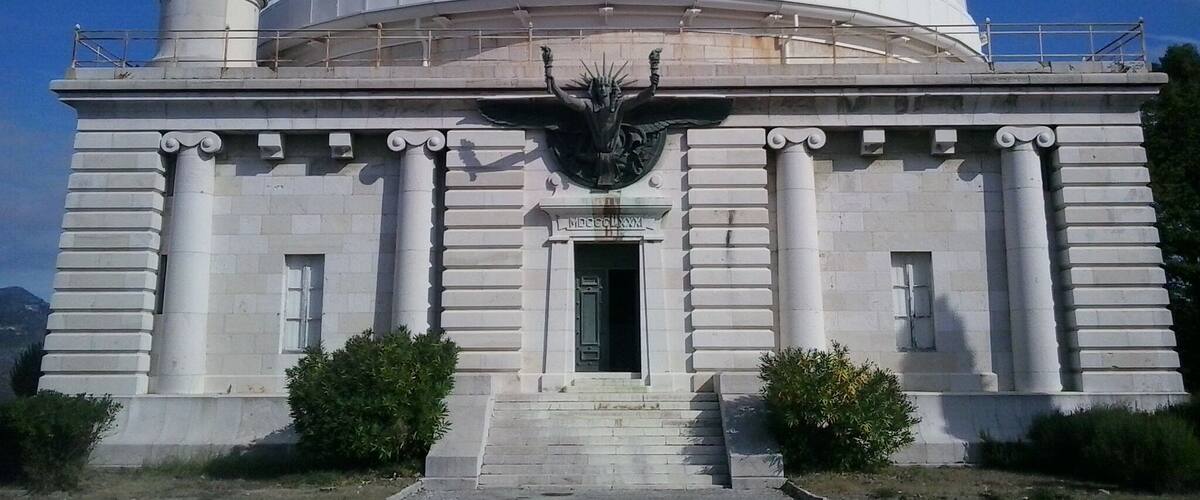A large white dome building with columns and a statue in front.