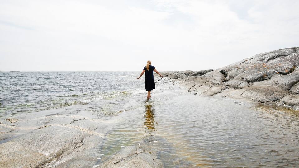 A person standing on rocky terrain by a body of water.