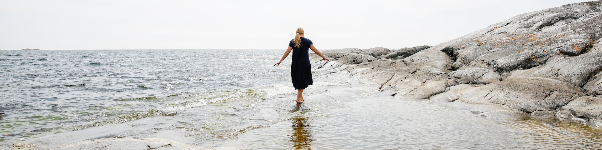 Sweden, Stockholm Archipelago, Sodermanland, Huvudskar, Rear view of mature woman wading in sea