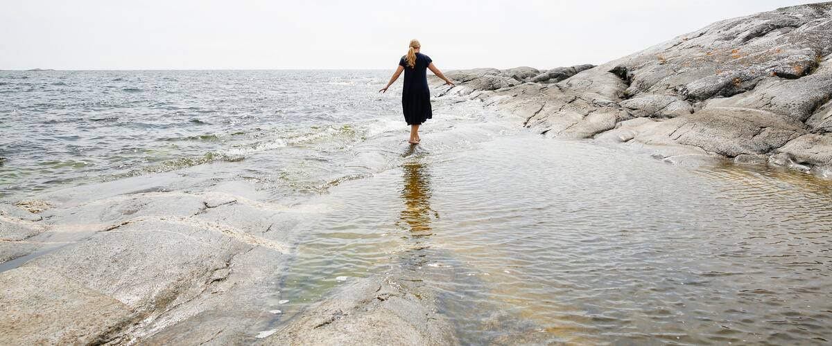 A person standing on rocky terrain by a body of water.