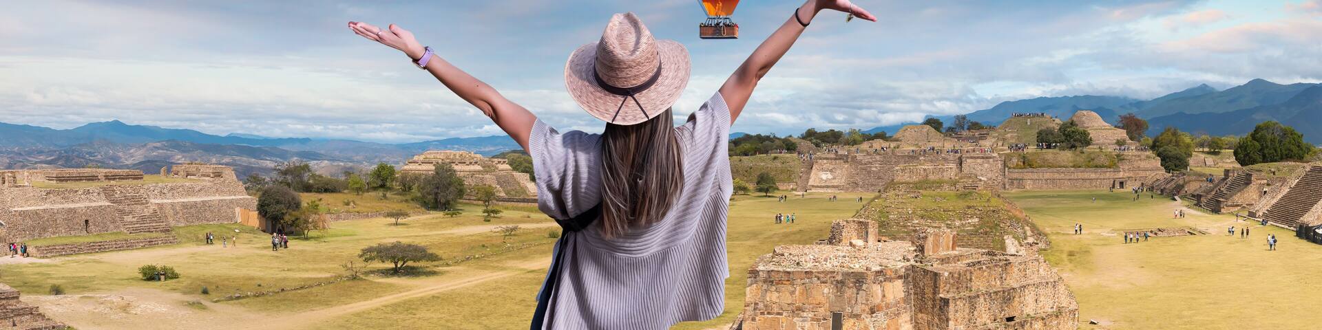 A person with arms raised, a colorful hot air balloon, and ancient ruins in the background.