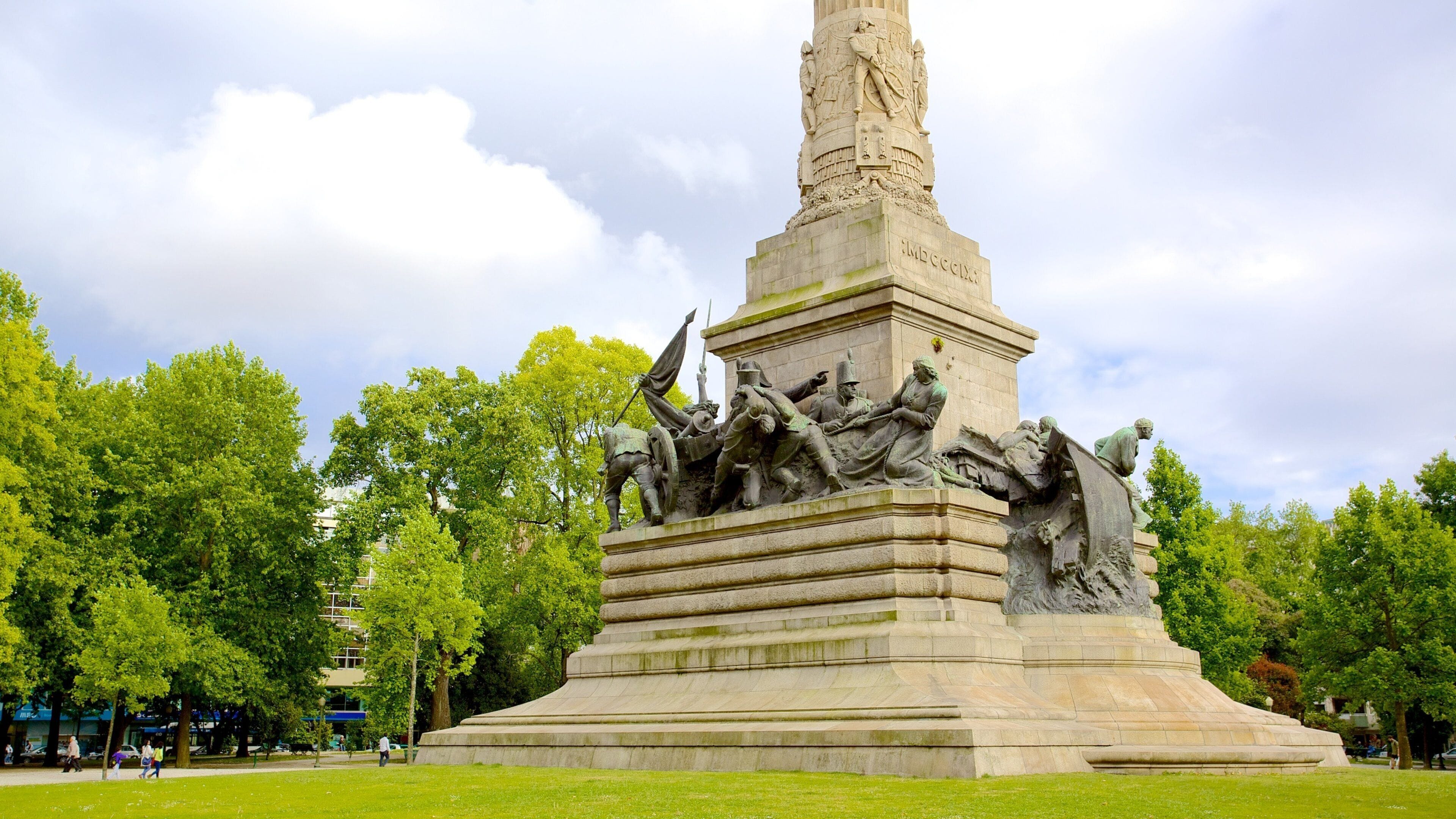 A large equestrian statue in a park with lush green trees and a clear sky.