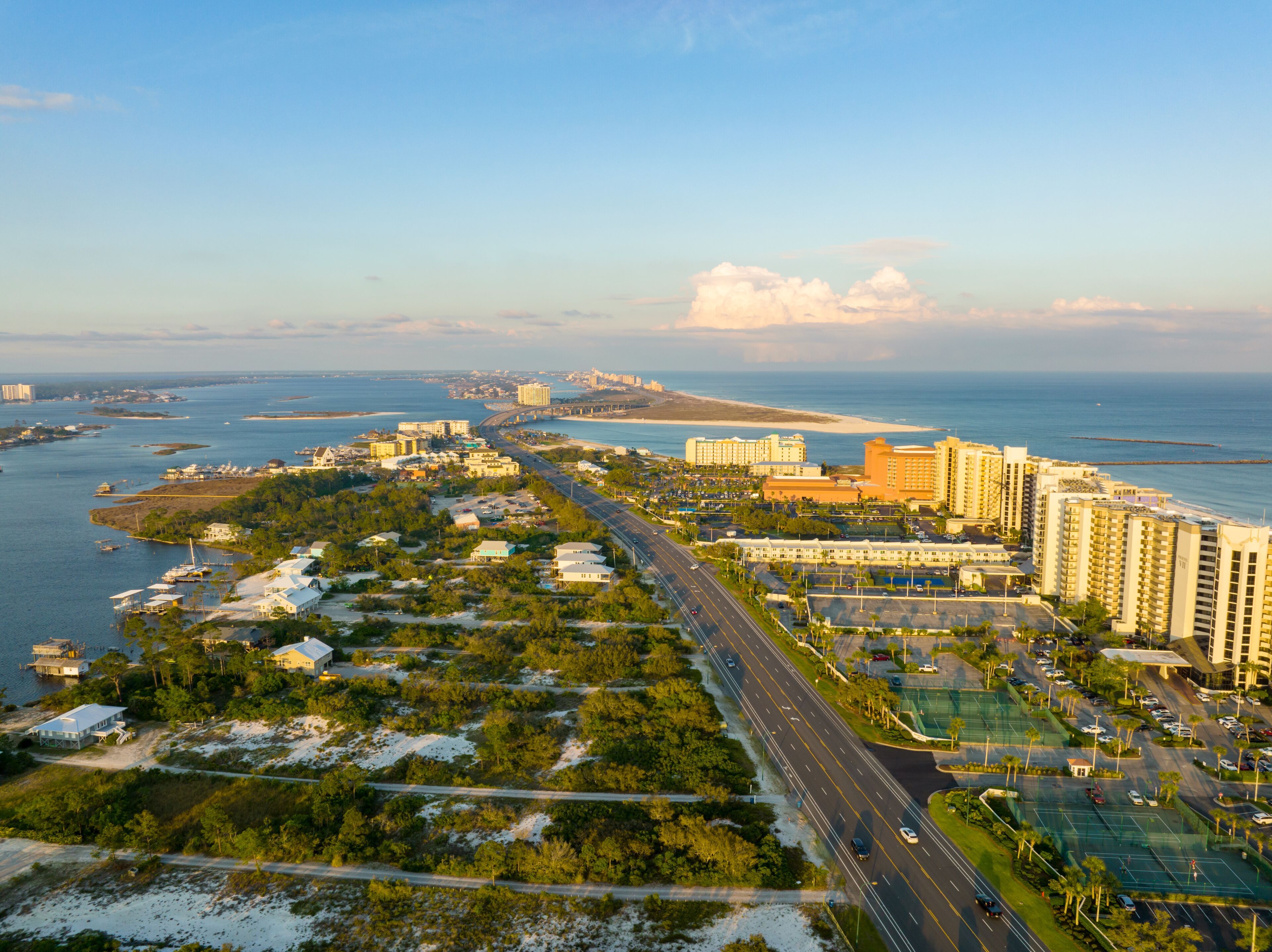 A coastal cityscape with a prominent highway, beachfront hotels, and a marina.