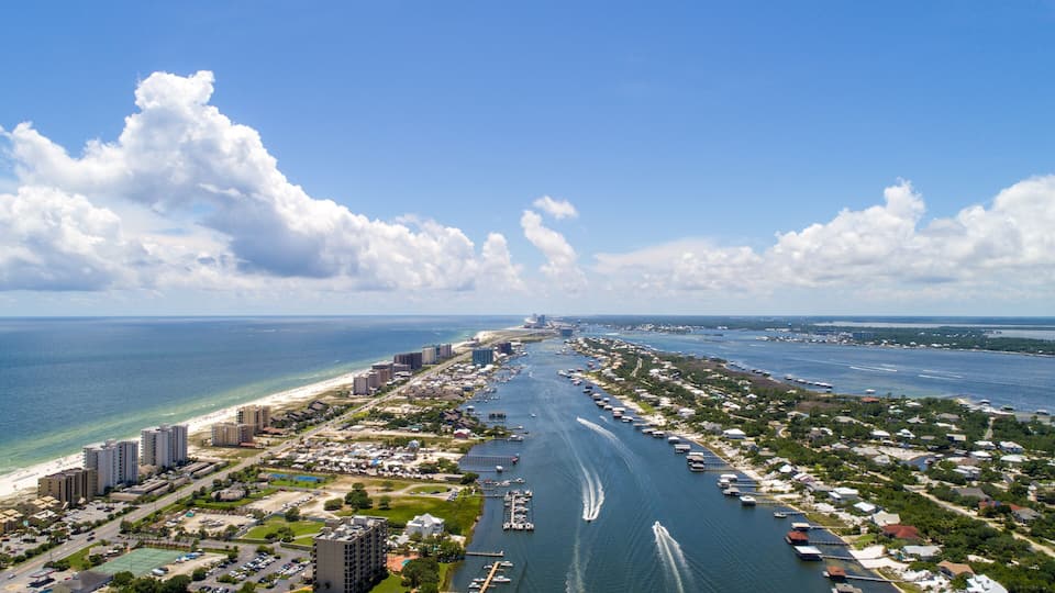 An aerial view of a coastal city with a marina, buildings, and a beach.