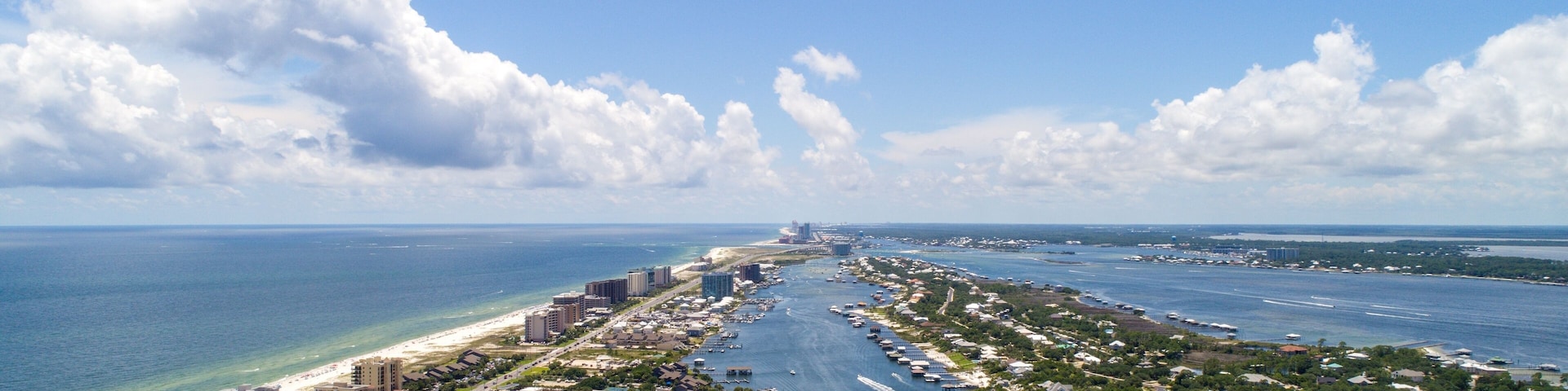 An aerial view of a coastal city with a marina, buildings, and a beach.