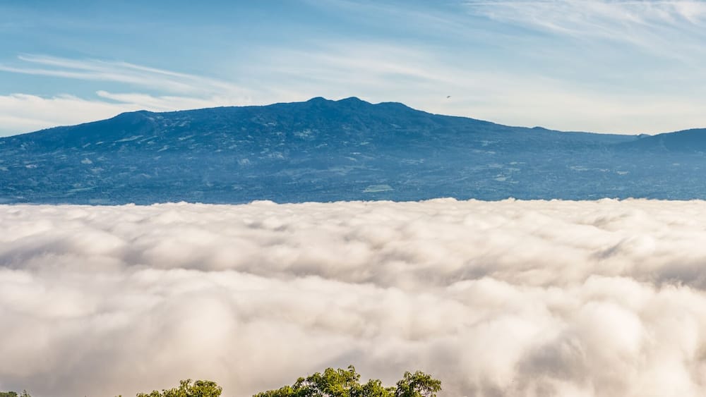 Une chaîne de montagnes surplombant une vallée enveloppée de nuages.
