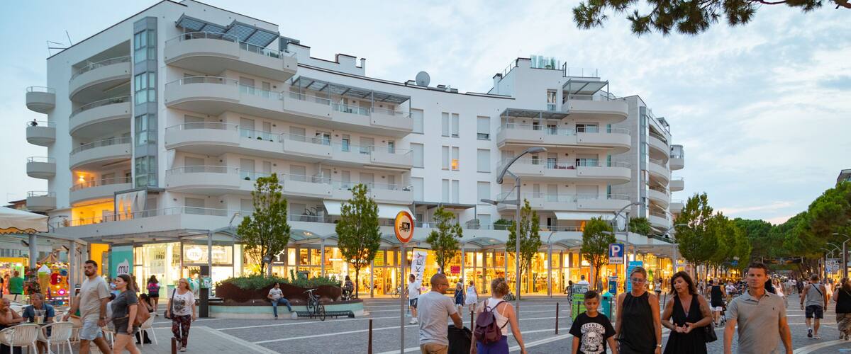 A busy urban street with pedestrians, shops, and modern buildings.