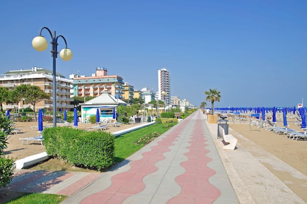 Una passeggiata lungomare con una pavimentazione piastrellata, ombrelloni da spiaggia e edifici sullo sfondo.