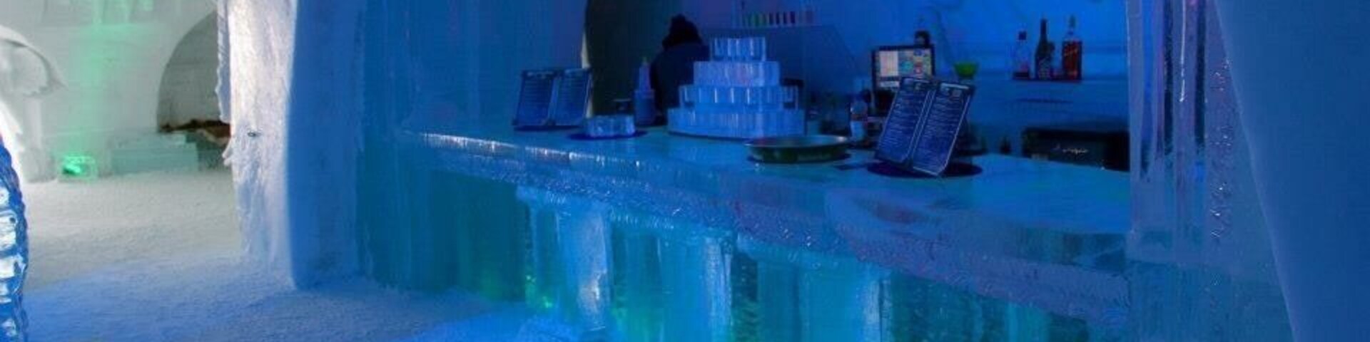 Un bar de hielo con interior iluminado en azul y esculturas de hielo.
