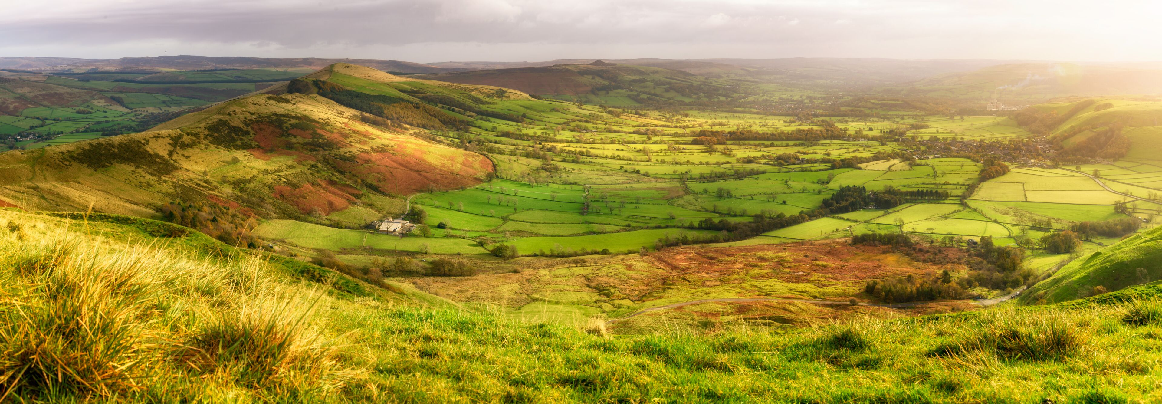 Rolling hills, a valley, and a small house in a rural landscape.