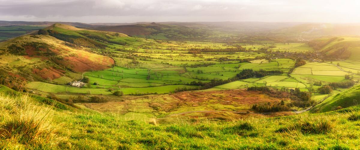 Rolling hills, a valley, and a small house in a rural landscape.