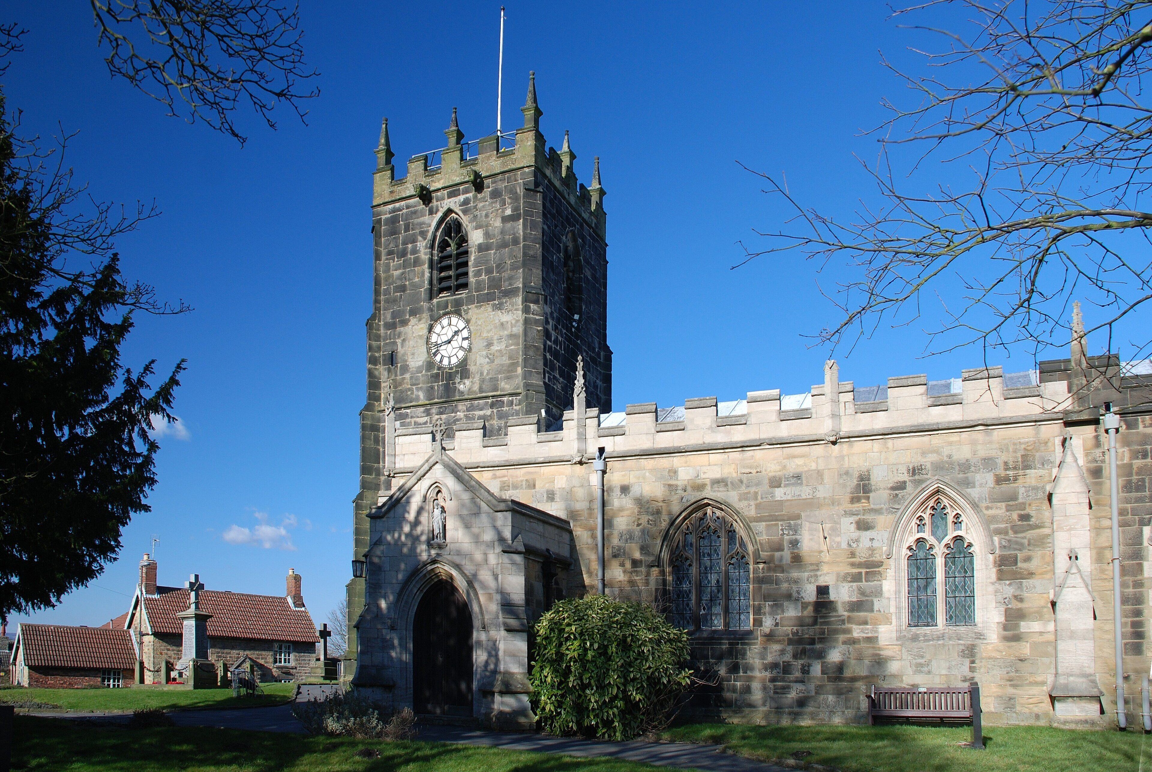 A historic church with a tall clock tower, arched windows, and a statue at the entrance.
