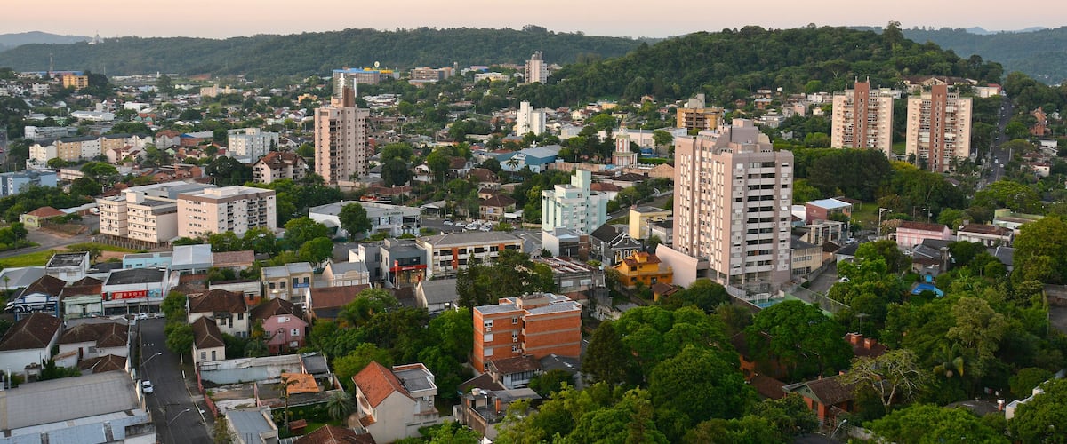 A cityscape with dense urban buildings, a prominent yellow building, and a backdrop of green hills.