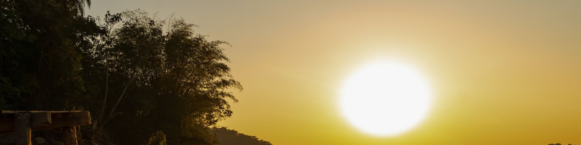 Beautiful sunrise over a small wooden pier and gallons, golden and clear sky, with fog on the freshwater beach of the Várzea das Flores dam, in Contagem, Minas Gerais, Brazil.