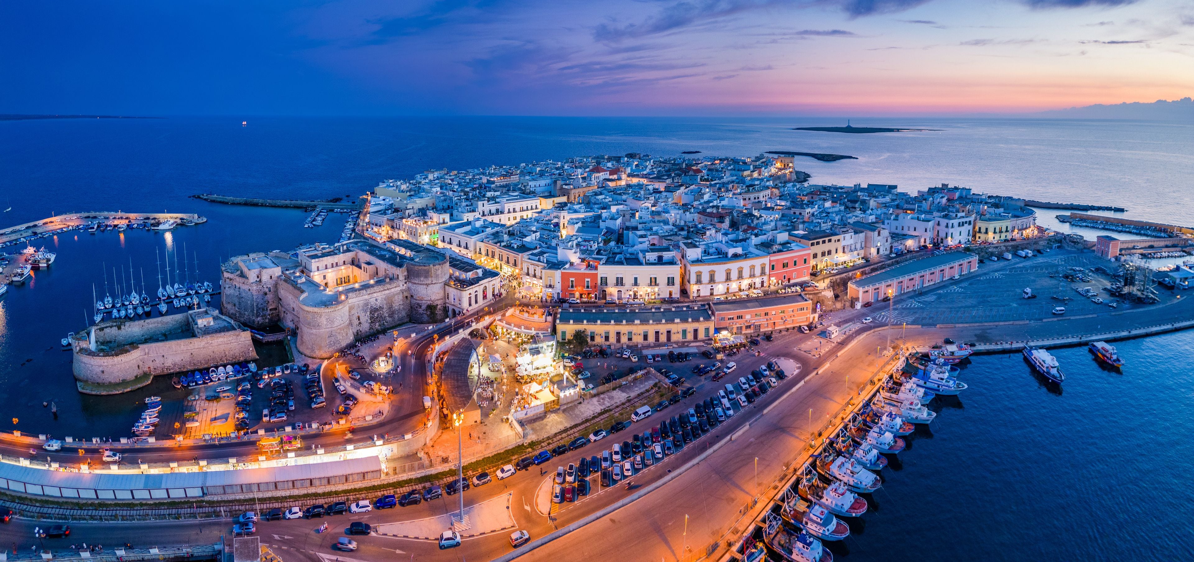 A coastal town with a historic fort, a marina, and a harbor at dusk.