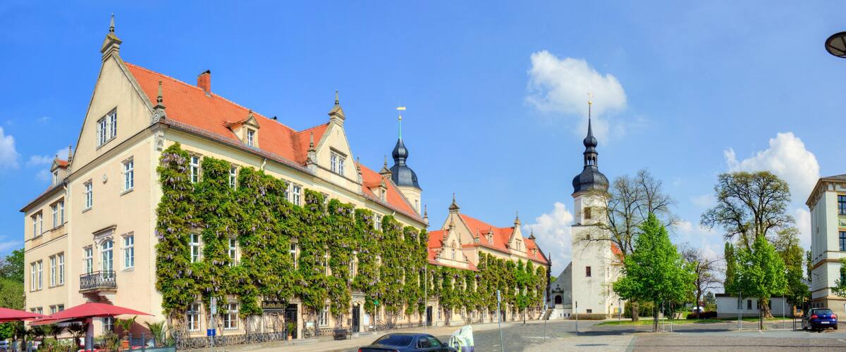 A historic building with red-tiled roofs and a tower with a spire.