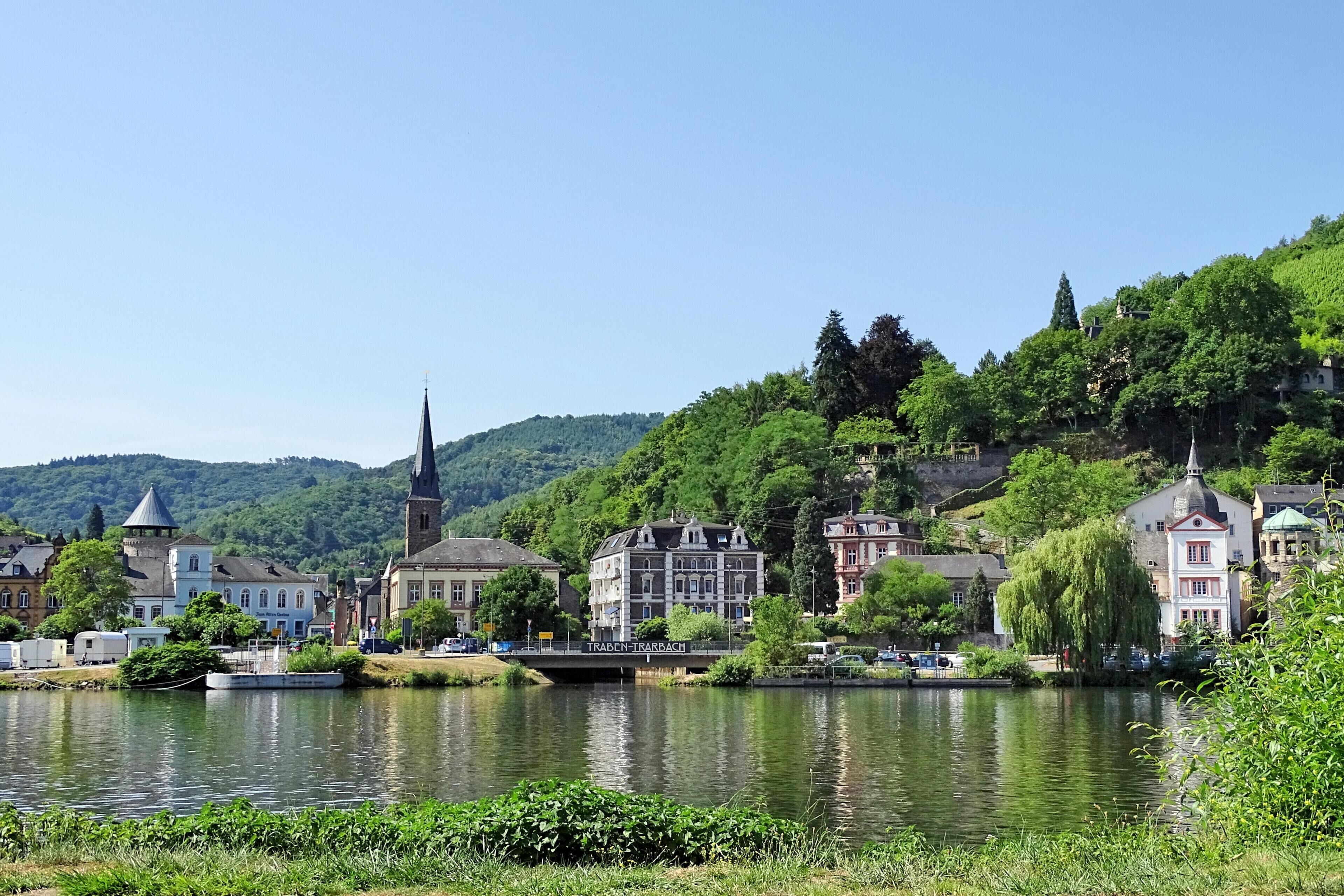 A riverside town with historic buildings, a church, and lush greenery.