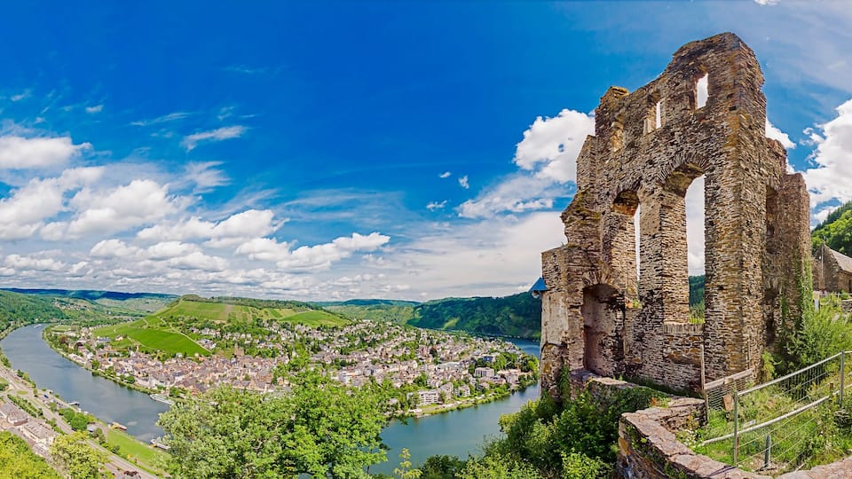 A panoramic view of a historic stone structure, a river, and a lush green valley.