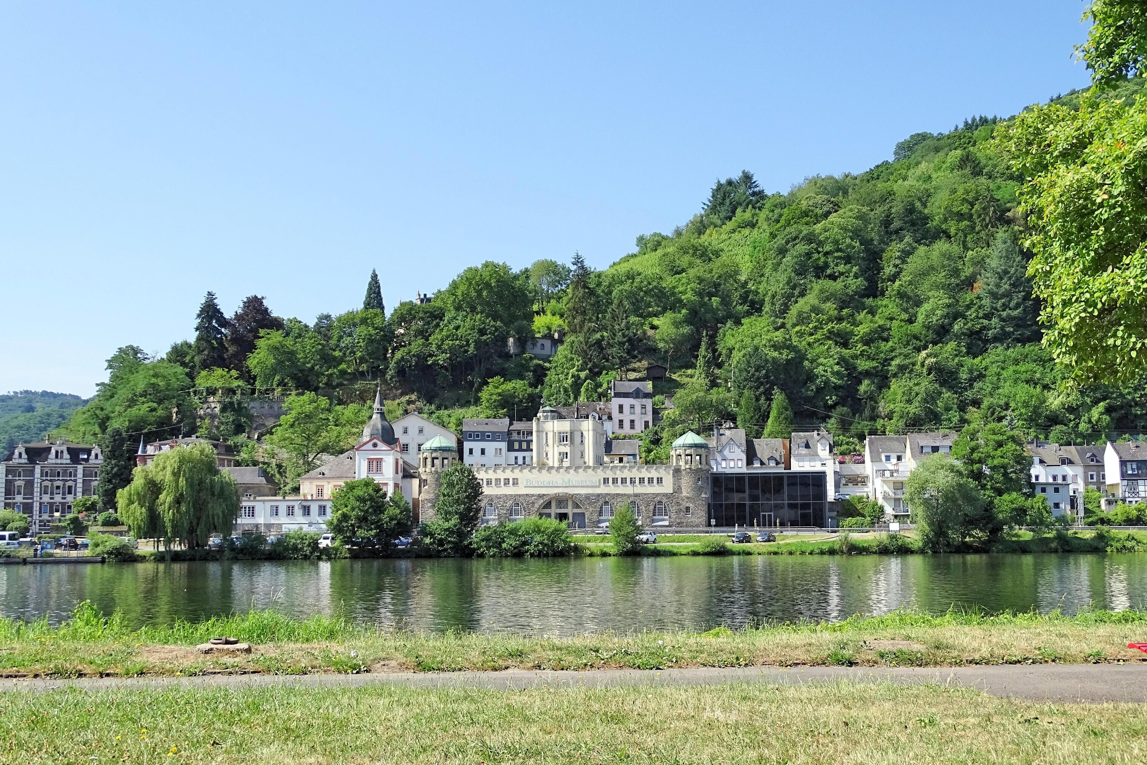 A riverside town with historic buildings and lush greenery.