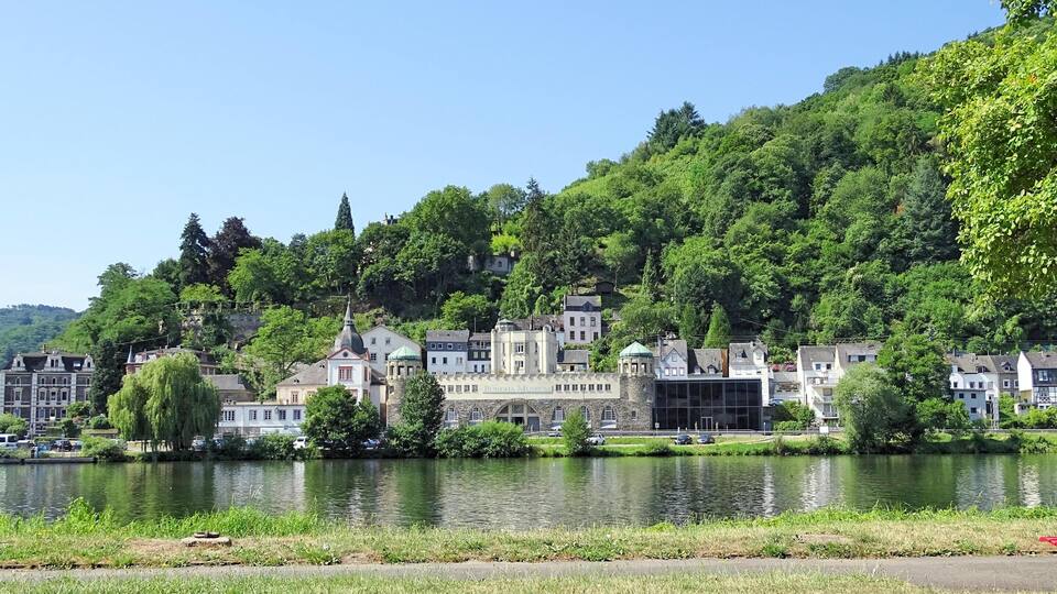 A riverside town with historic buildings and lush greenery.
