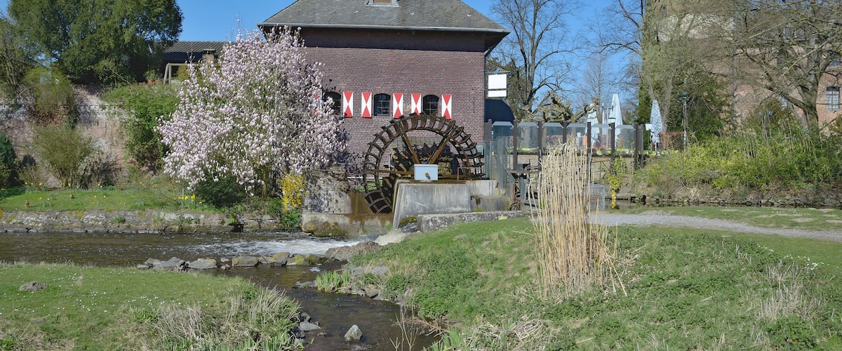 A historic building with a watermill, a stream, and a tower.
