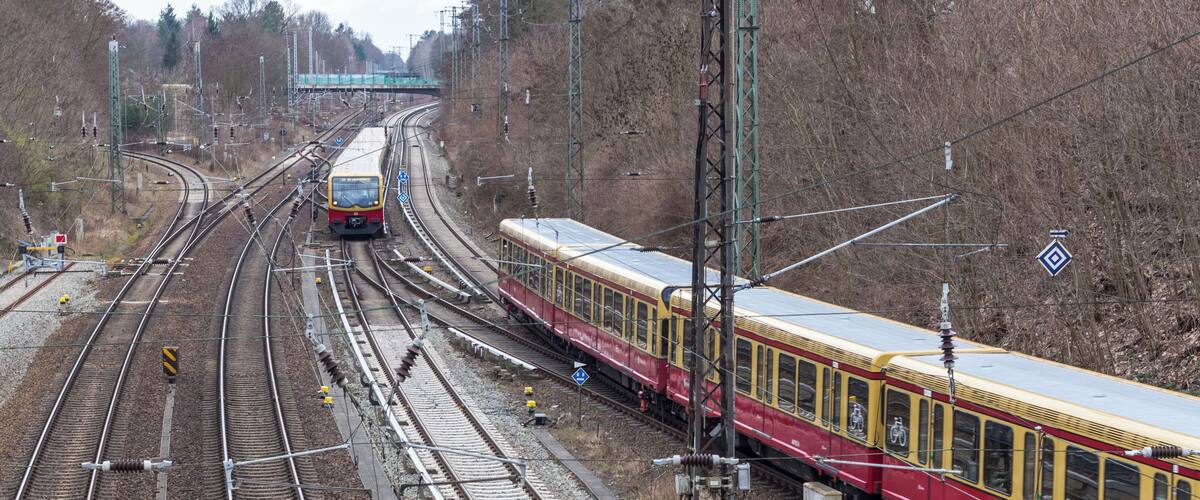 A railway junction with multiple tracks and a red and yellow train passing through.