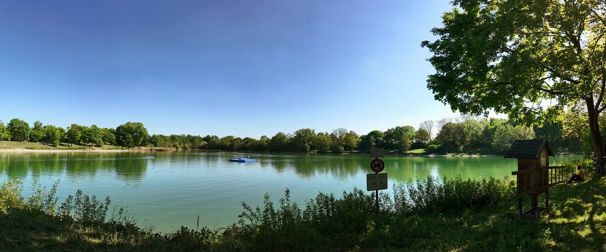 A calm lake surrounded by trees and a wooden structure on the right.