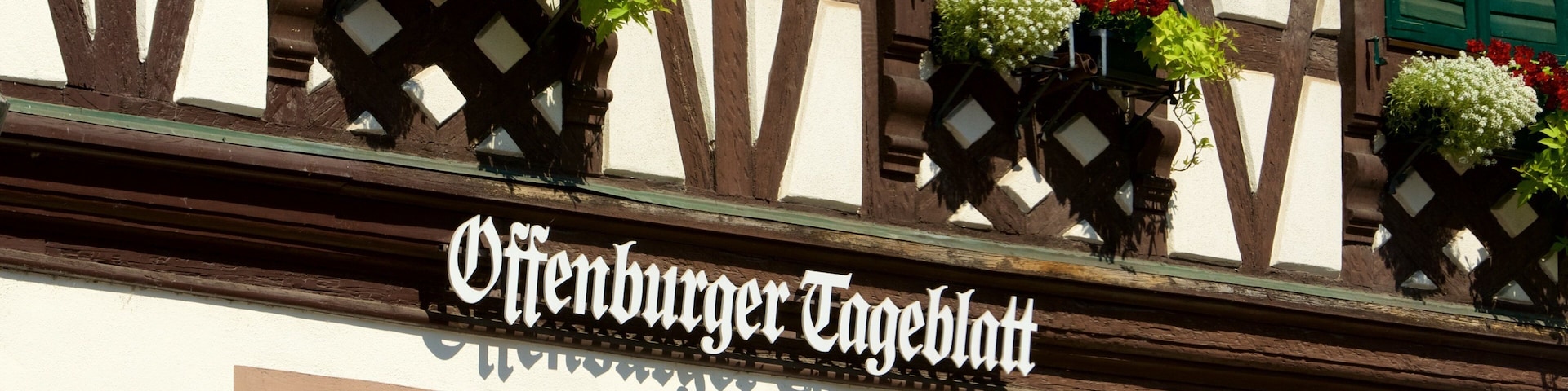 Um edifício com uma placa que diz 'Oberenburger Tagelblatt' e persianas verdes.