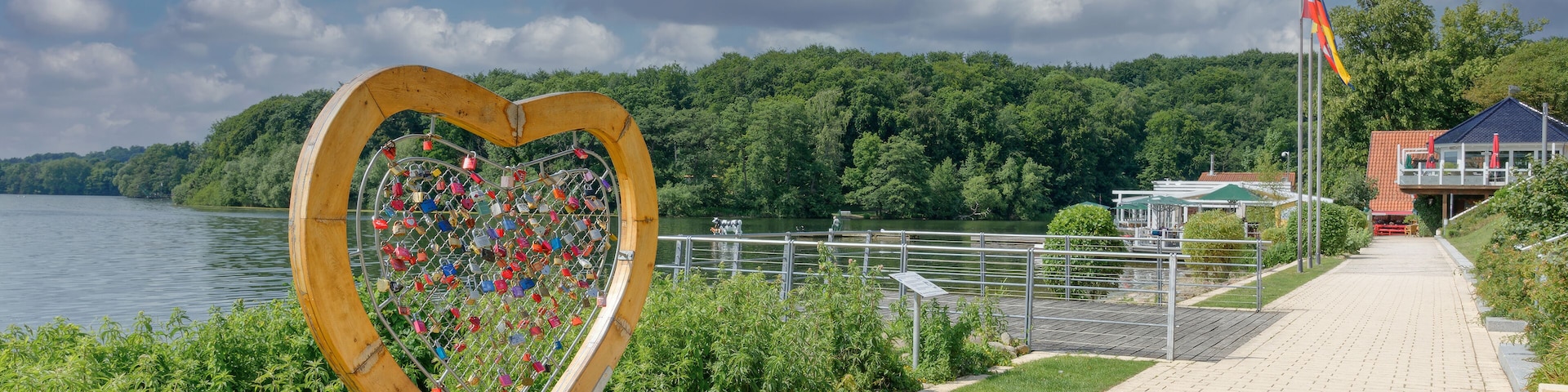 Escultura em formato de coração com nomes gravados ao longo de um calçadão à beira do lago.