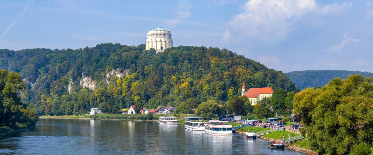 A river with boats, a water tower, and a church on a hill.