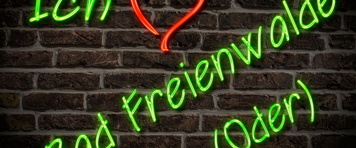 A neon sign on a brick wall with the text "Ich Bad Freienwalde (Oder)" and a heart symbol.