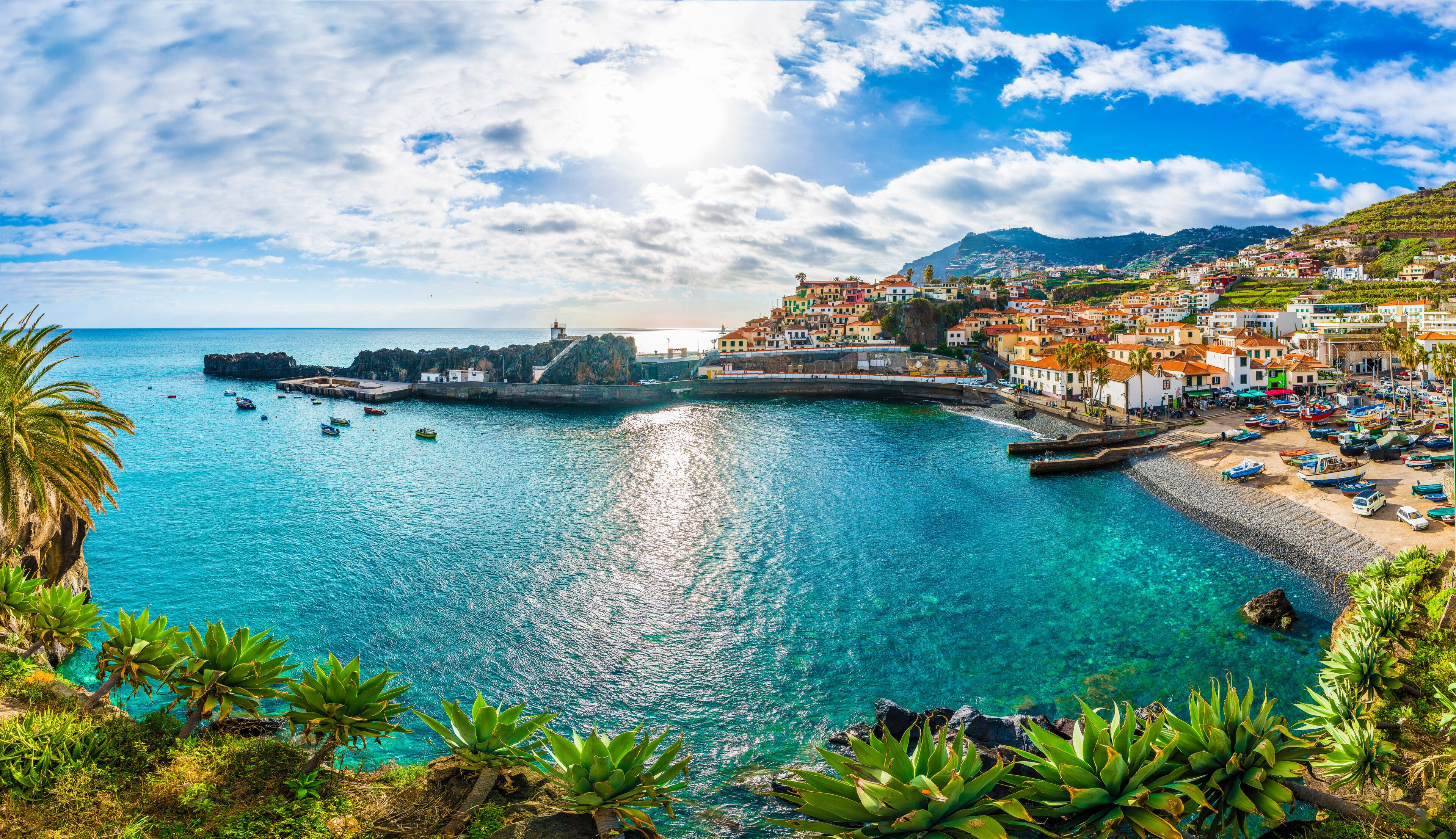 Uma vila costeira com um porto, barcos e um farol.