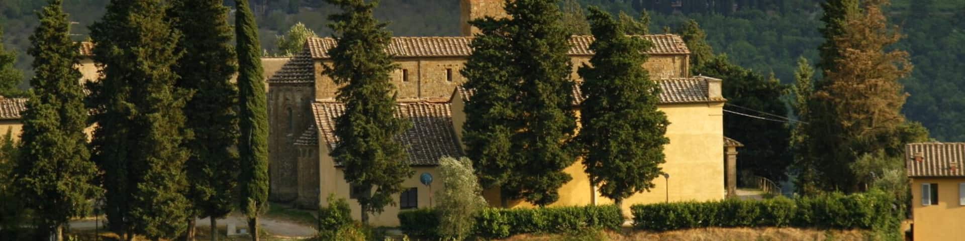 A church with a bell tower, surrounded by trees and hills.