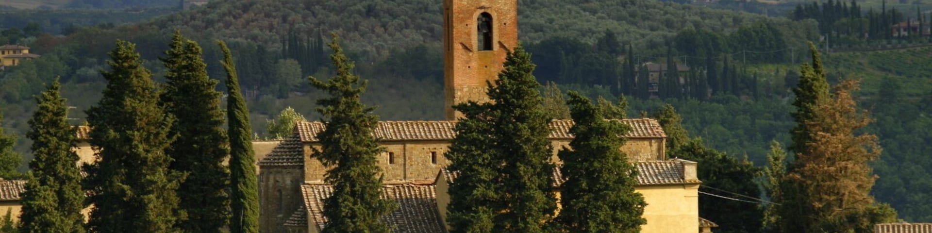 Una iglesia con un campanario, rodeada de árboles y colinas.