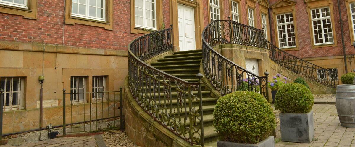 A historic building with a grand staircase, large windows, and a coat of arms.