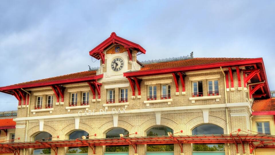 A building with a clock tower, red roof, and arched windows.